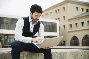 Professional working on a laptop outdoors.